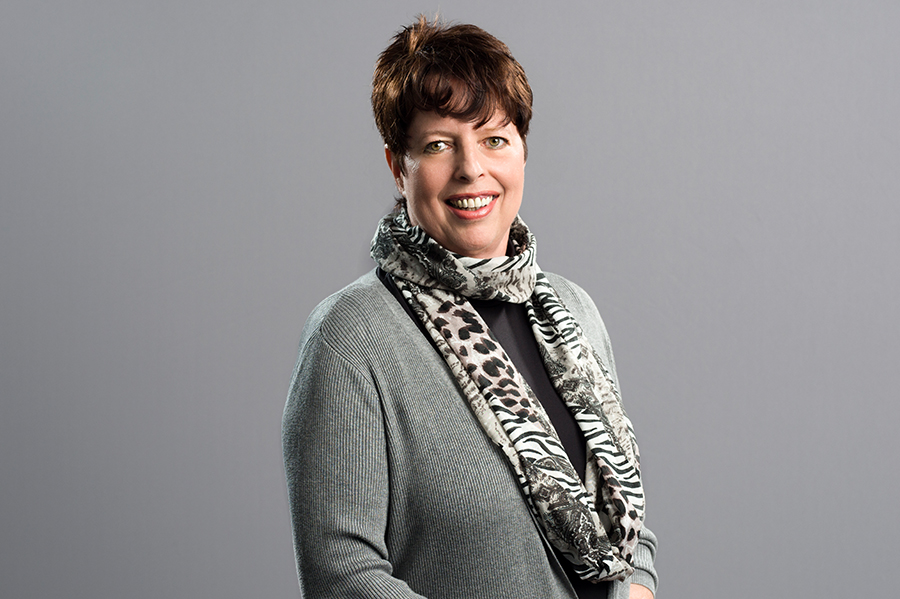 Woman with a smile wears a fashionable scarf around her neck.